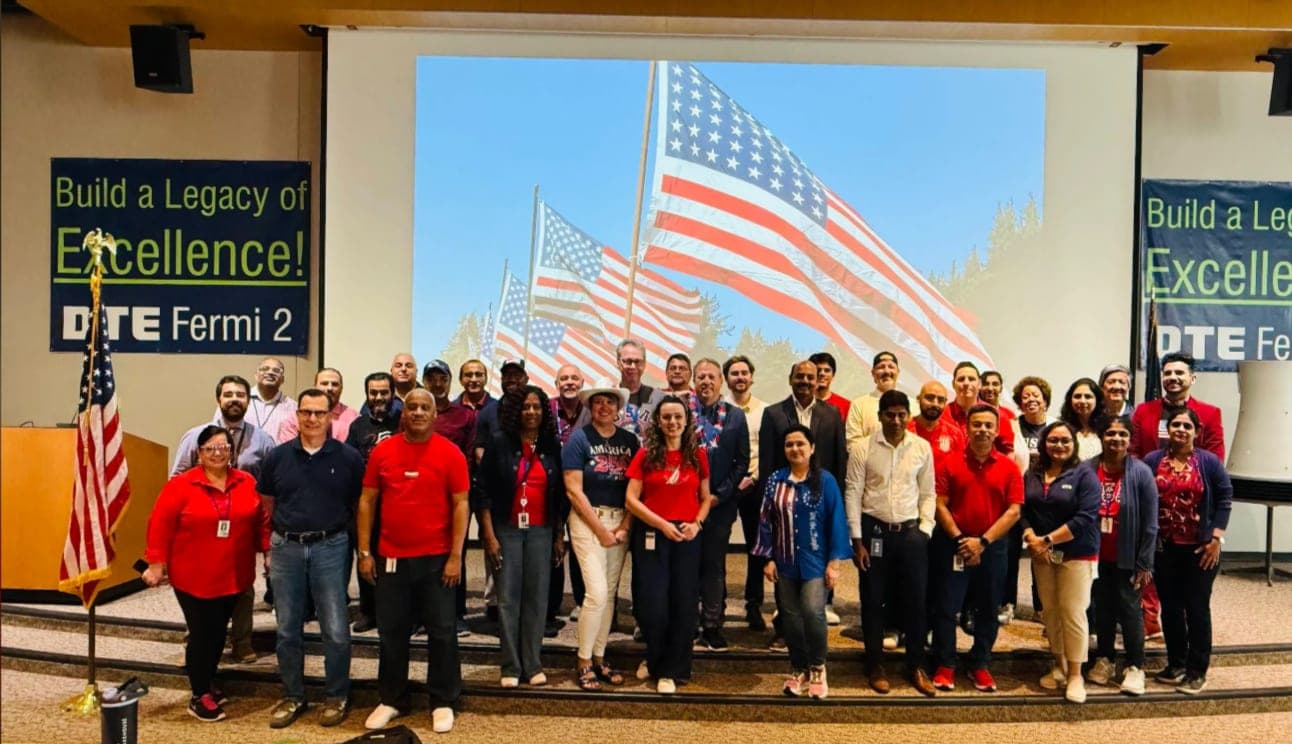 Ahmad's team posing in red, white, and blue outfits in front of a DTE Fermi 2 banner