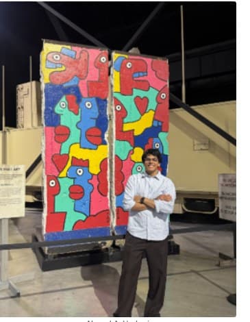 Ahmad standing in front of a Berlin Wall exhibit piece, from DTE's Student Spotlight feature